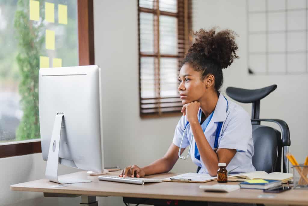 African american female doctor sitting in front of computer at her clinic office