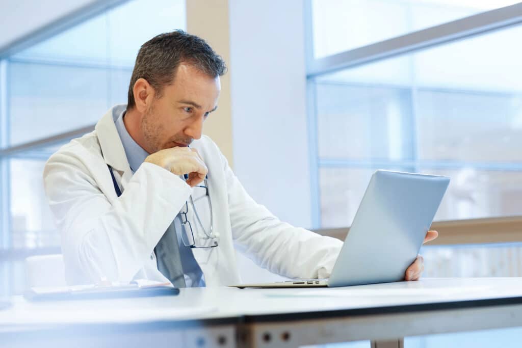 Doctor in hospital office working on laptop