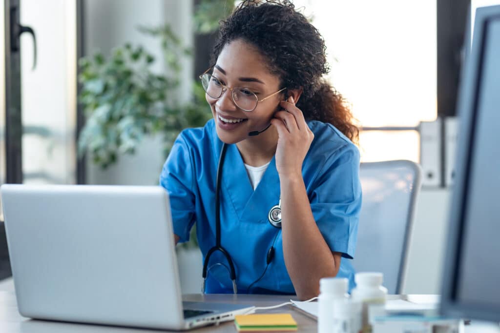 Shot of attractive afro female doctor talking while explaining medical treatment to patient through a video call with laptop in the consultation.