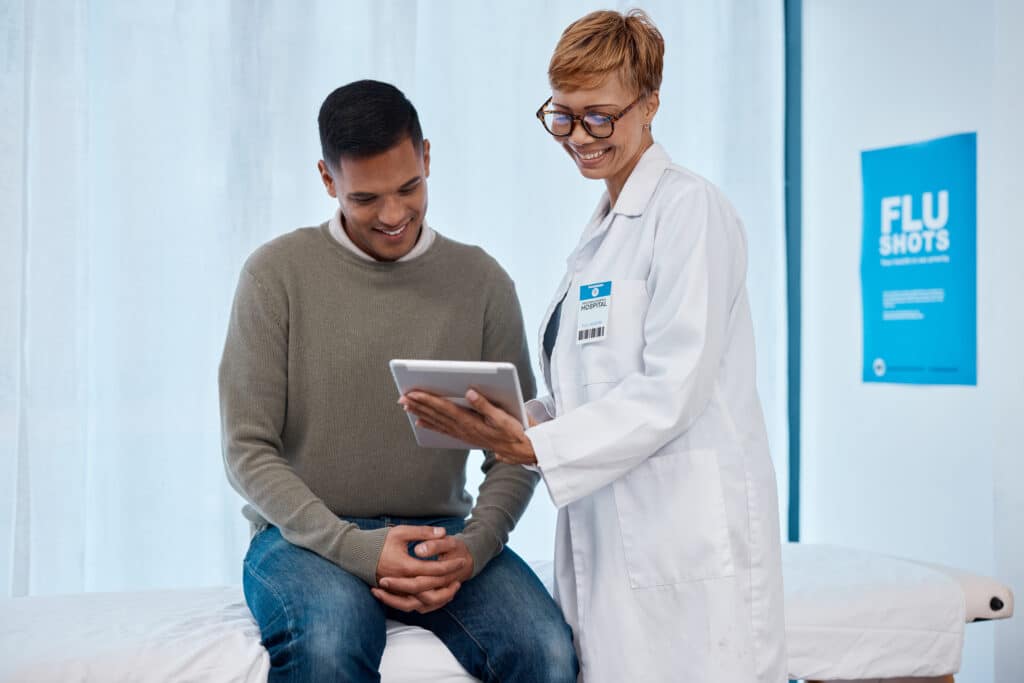 Tablet, black woman and patient consulting doctor in hospital for health results. Healthcare consultation, technology or happy senior female or medical physician with touchscreen while talking to man.
